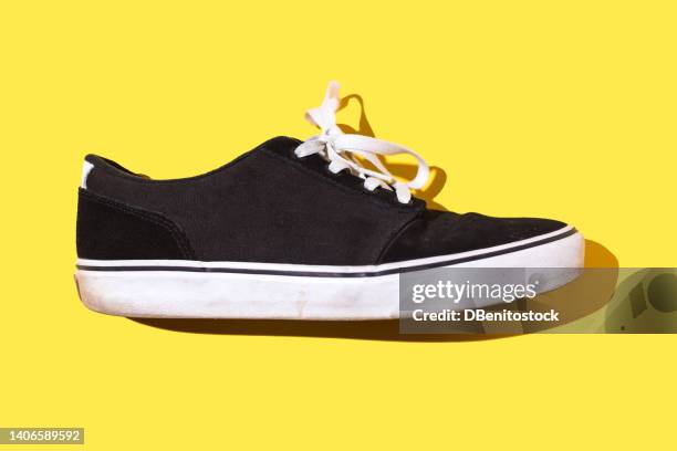 black and white canvas and rubber surfer and skater sneakers with white laces, on a yellow background. concept of skateboarding, surfing, fashion, sneakers, modern and retro. - famous 80's fashion clothes stock-fotos und bilder