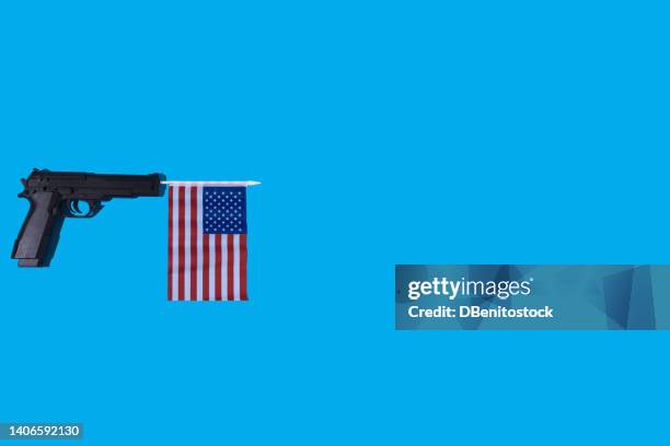 black pistol with the flag of the united states of america coming out of the barrel, on the left side, on a blue background. weapon, murder, violence, shooting, police, bodyguard, hitman concept. - hitman stock pictures, royalty-free photos & images