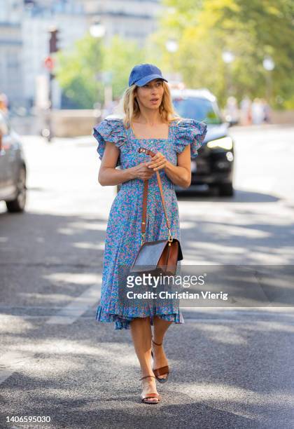 Alexandra Golovanoff seen wearing blue cap, dress with floral print, Louis Vuitton bag outside Patou during Paris Fashion Week on July 03, 2022 in...