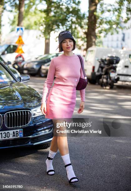 Guest is seen wearing bucket hat with logo print, pink jumper, skirt outside Patou during Paris Fashion Week on July 03, 2022 in Paris, France.