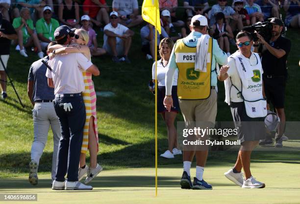 Poston of the United States celebrates with fiance Kelly Cox after putting in to win on the 18th green during the final round of the John Deere...