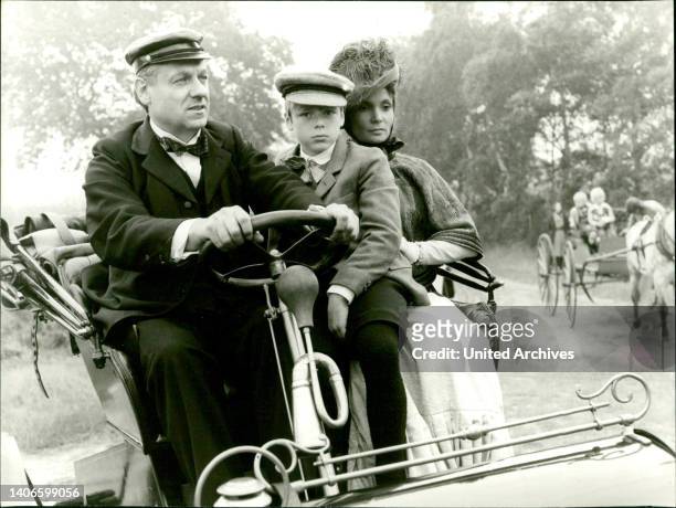 Henry Ford, sein Sohn Edsel und seine Frau Clara fahren in dem neuesten Ford-Automobil auf einer Landstraße in Michigan spazieren. V.l.: .
