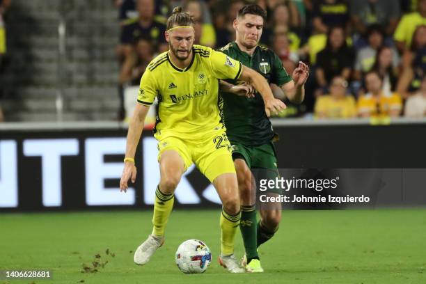 Walker Zimmerman of Nashville SC battles for the ball with Jarosław Niezgoda of Portland Timbers during the game at GEODIS Park on July 03, 2022 in...