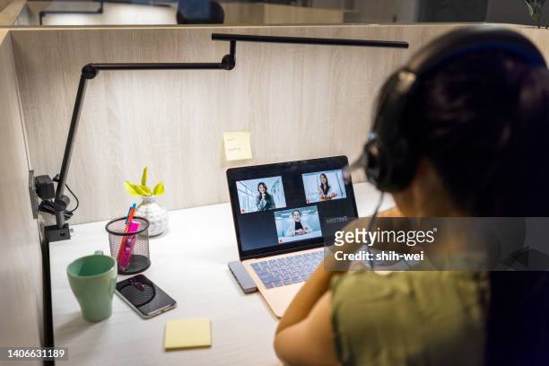asian business woman sits on her personal desk, using her laptop and earphone to have a face time meeting - financial advisor virtual stock pictures, royalty-free photos & images