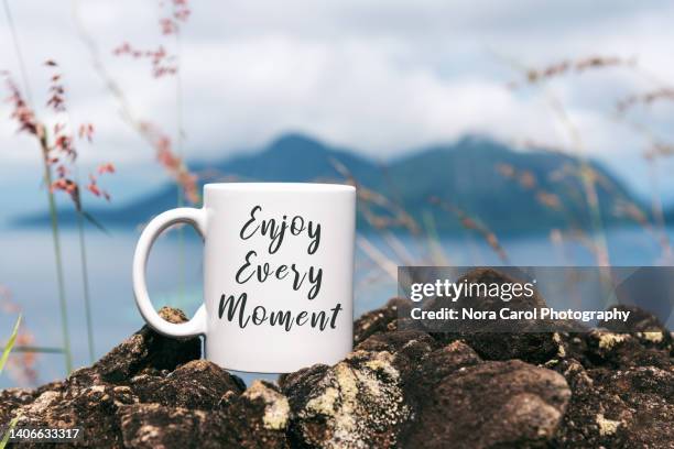 enjoy every moment text on a coffee mug with tropical ocean in the background - motivational quotes stock pictures, royalty-free photos & images