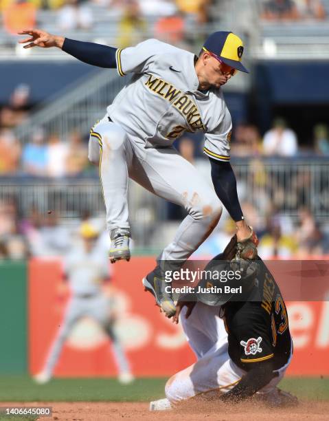 Ke'Bryan Hayes of the Pittsburgh Pirates slides in safely for a stolen base past a tag attempt by Willy Adames of the Milwaukee Brewers in the fifth...