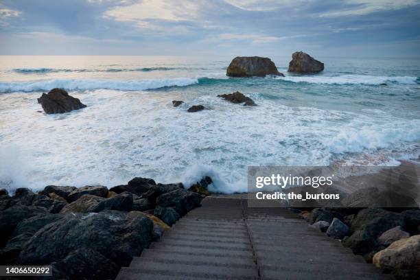 staircase to the sea and splashing waves - maré alta imagens e fotografias de stock
