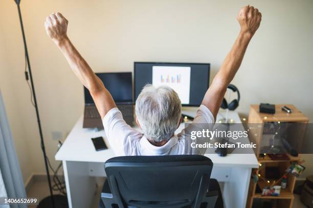 senior man stretching working from home on a remote job in a home office - part time worker stock pictures, royalty-free photos & images