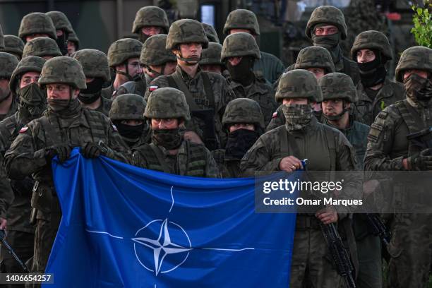 Polish soldiers hold a NATO flag during a family photo after a training demonstration with the NATO multinational battle group eFPon at the Orzysz...