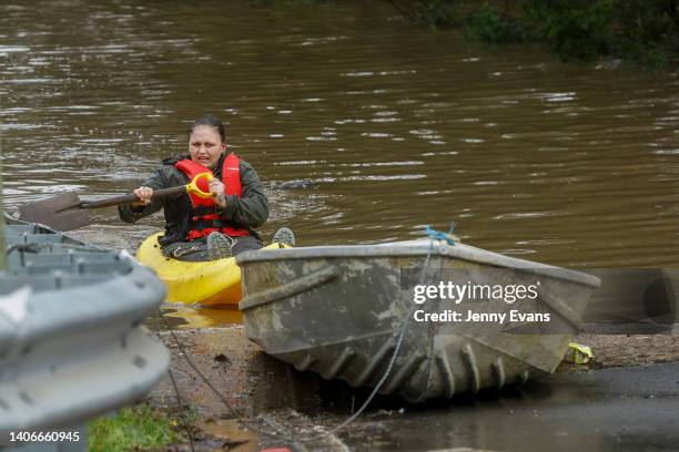 Woman kayaks across a flooded street in Bligh Park on July 04, 2022 in Sydney, Australia. Thousands of residents were forced to leave their homes...