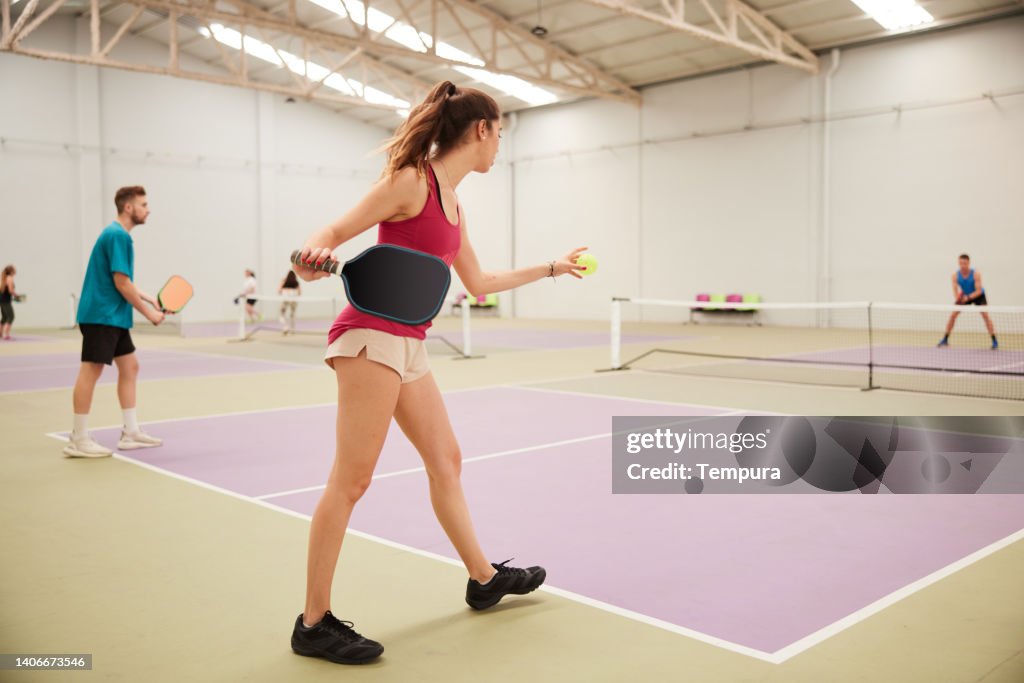 A pickleball female player is serving on a court.