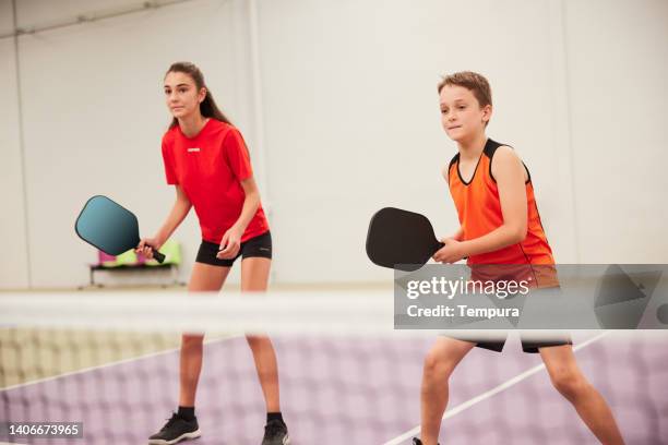 teenagers are playing pickleball. - kid pickleball stock pictures, royalty-free photos & images