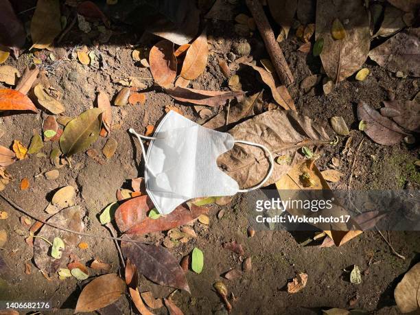disposed used face mask lies on the street - fall prevention photos et images de collection