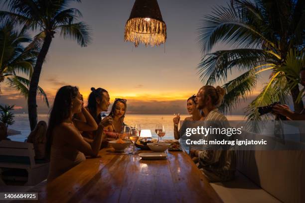 multirassische freunde beim abendessen im strandrestaurant während des sonnenuntergangs - thailand strand stock-fotos und bilder