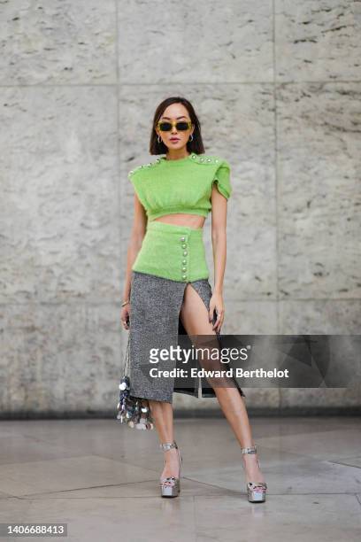 Chriselle Lim wears yellow sunglasses, silver earrings, a green fluffy cut-out waist / buttoned / sleeveless t-shirt, a gray slit / split knee skirt,...