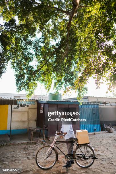 adult male with bicycle under big tree at the market smiling - zambia stockfoto's en -beelden