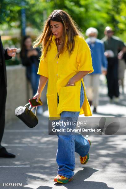 Heloïse Salessy wears a yellow / red / black striped print pattern pearls necklace, a yellow sponge oversized / short sleeves oversized shirt, blue...