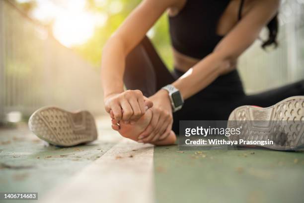 soft focus woman massaging her painful foot while exercising. running sport injury concept. - human foot stockfoto's en -beelden