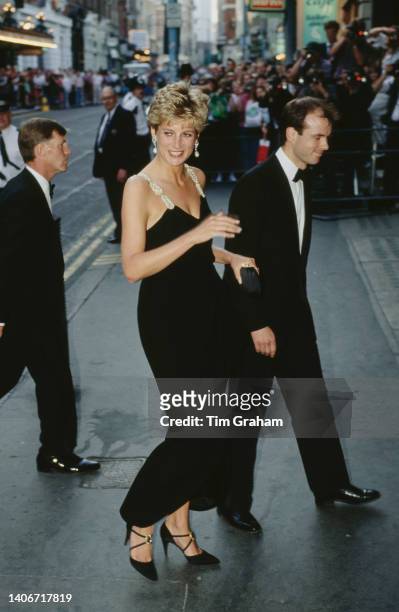 Princess Diana wears a black low cut evening dress as she arrives at the London Coliseum Theatre to see The Taming of the Strew in London, England,...