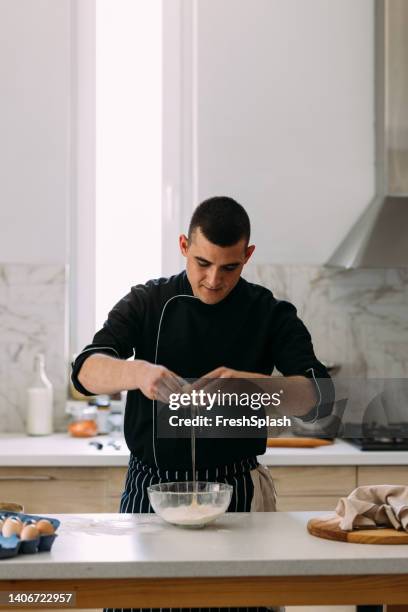 smiling caucasian pastry chef making the dough, cracking eggs into a bowl - pastry chef stock pictures, royalty-free photos & images