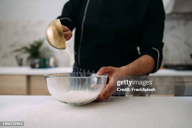 anonymous caucasian cook preparing dessert, pouring flour into a bowl - measuring cup imagens e fotografias de stock