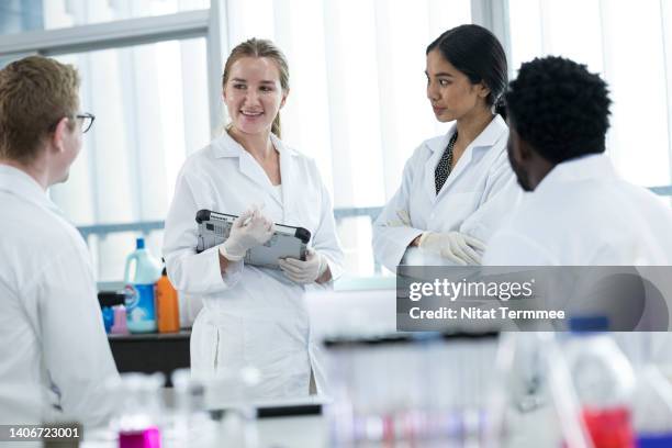 promote and foster collaborative research in laboratory. diversity of scientists or researchers discussing their research result data in medical laboratory. they are wearing lab coats. - microbiologie photos et images de collection