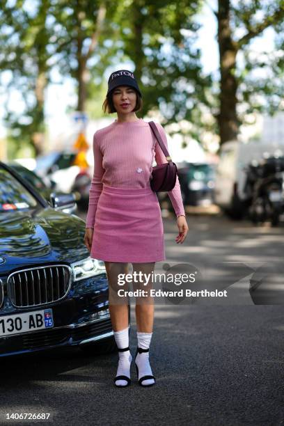 Guest wears a black with white embroidered logo bob hat from Patou, a pale pink ribbed long sleeves t-shirt from Patou, a burgundy shiny leather...