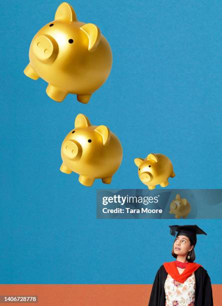 graduate looking up at piggy bank - student loan stockfoto's en -beelden