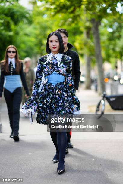 Guest wears a black with purple / white / orange flower print pattern long sleeves / puffy short dress with a white lace collar, a pale blue large...