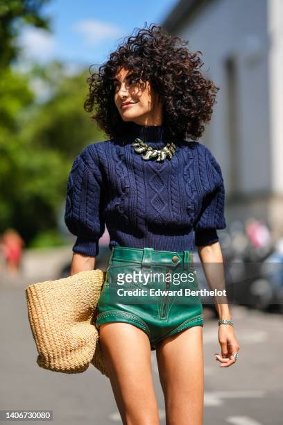 Guest wears a navy blue embossed pattern high neck / puffy short sleeves / wool pullover, a silver and gold large pendant necklace, a beige wicker...