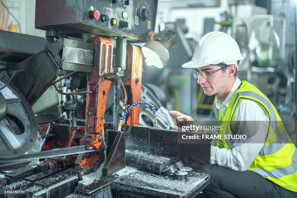 Male engineer wearing white safety helmet Inspecting and controlling machines to work as intended