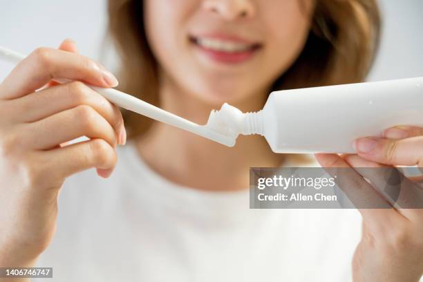 asian young woman brushing her teeth in front of mirror - zahnpasta stock-fotos und bilder