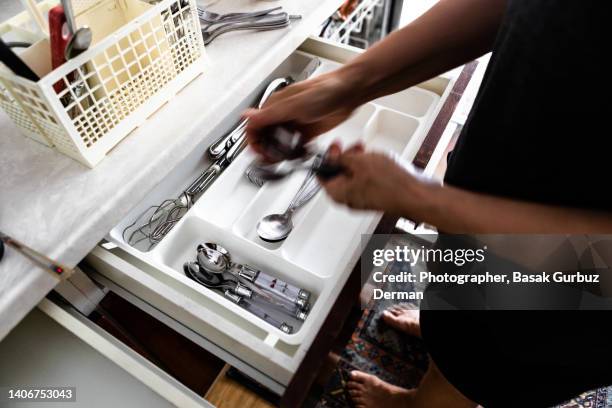 close-up of woman arranging spoons in cutlery drawer - tongs stock pictures, royalty-free photos & images