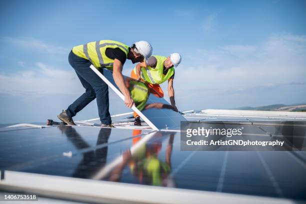 coworking-elektriker installieren photovoltaikanlage auf einem lagerdach. - solar system stock-fotos und bilder