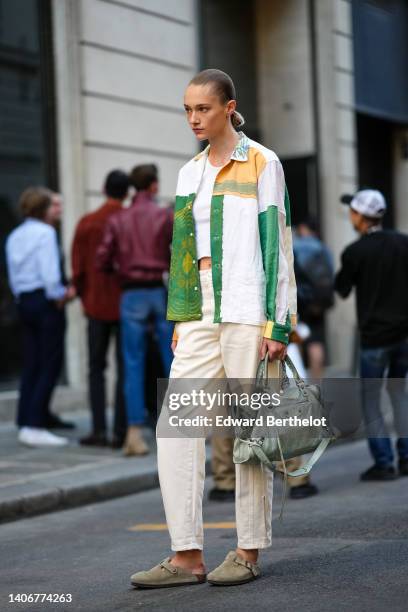 Model wears a white cropped tank-top, a white with dark green / orange print pattern open shirt, white latte denim large pants, a pale gray leather...