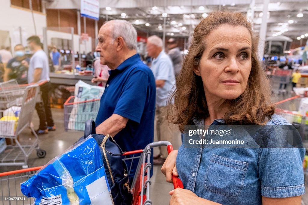 Mature woman holding her shopping cart waiting in line to pay at a megastore