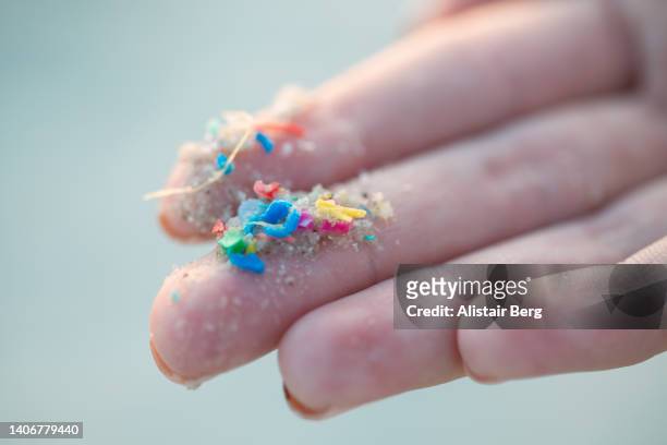 researcher holding small pieces of micro plastic pollution washed up on a beach - granule plastique photos et images de collection