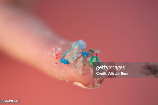 woman holding small pieces of micro plastic pollution washed up on a beach - mikroplastik stock-fotos und bilder