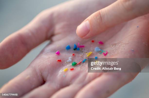 woman holding small pieces of micro plastic pollution washed up on a beach - nature shallow depth of field stock pictures, royalty-free photos & images