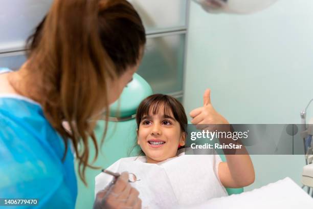 dentist at the dentist's office examining the girl's teeth - fluor stockfoto's en -beelden
