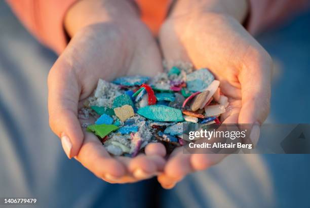 researcher holding collection of ocean plastic pollution on a beach - mikroplastik stock-fotos und bilder
