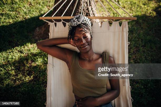 woman relaxing in a hammock - trädgård hängmatta bildbanksfoton och bilder