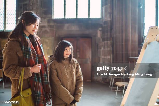 mom & daughter reading some information on display board while visiting a cathedral. - museum tour stock pictures, royalty-free photos & images