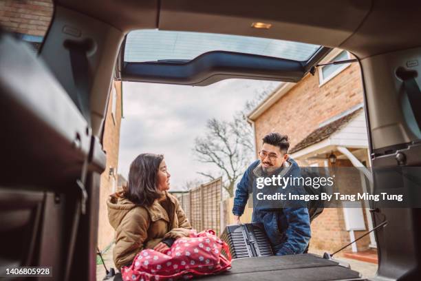 lovely girl assisting her daddy loading the bag & suitcase to the car trunk for their road trip - unloading stock pictures, royalty-free photos & images