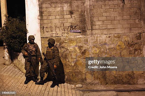 Mexican army soldiers stand guard near a suspected drug-related murder site March 3, 2012 in Acapulco, Mexico. A forensics team excavated five...