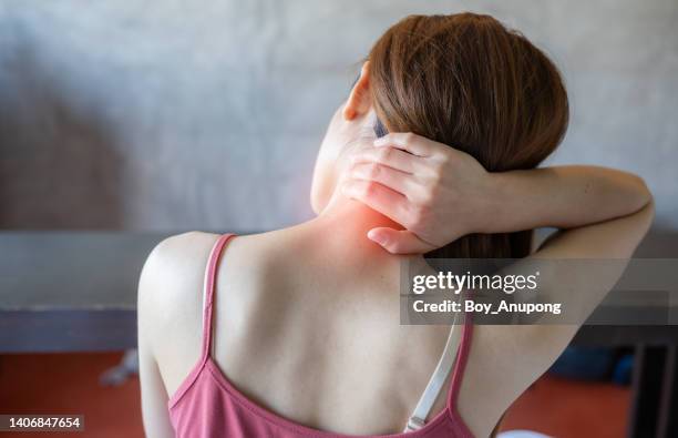 rear view of young woman having neck pain. - cuello mujer fotografías e imágenes de stock