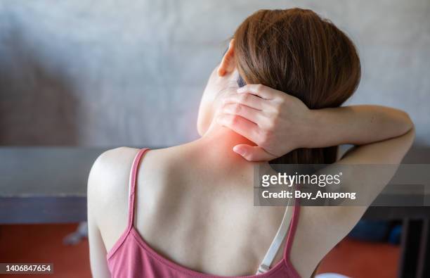 rear view of young woman having neck pain. - neckache stock pictures, royalty-free photos & images
