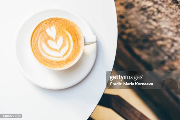 close-up of coffee cup with cappuccino on table. - coffee art stockfoto's en -beelden