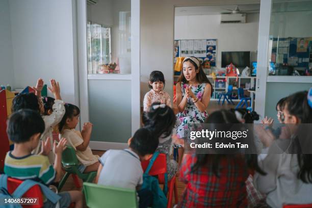 asian montessori preschool student introducing herself in front of her classmate standing beside teacher in classroom first day in school - surrounding support stock pictures, royalty-free photos & images