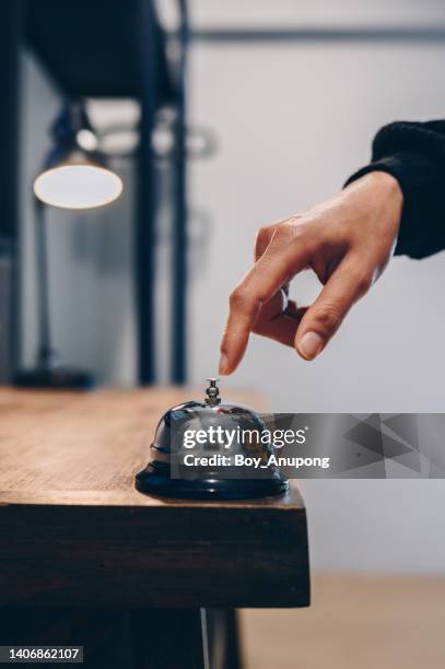 close up of someone hand trying to call hotel reception by ringing front desk bell. - symbole sonne photos et images de collection